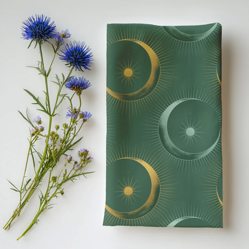 Four-piece cloth napkin set featuring a celestial print of radiant golden crescent moons and pale sunburst orbs against a rich emerald green background. Each napkin displays symmetrical, glowing motifs inspired by lunar phases and cosmic geometry. The fabric is neatly folded to showcase the repeating pattern, with a soft matte finish and fine detailing, perfect for mystical or magical table settings, altar decor, or celestial-inspired dining aesthetics.